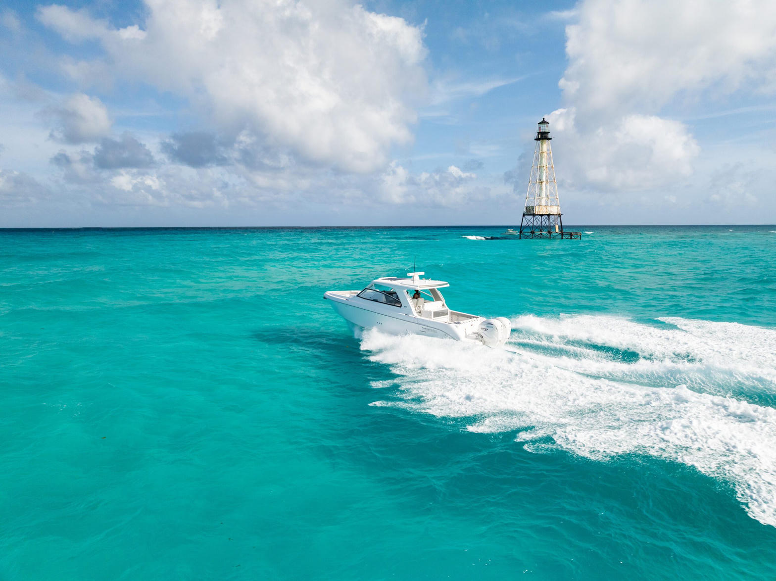 Sportfishing boat in turquoise Florida Keys water near a lighthouse
